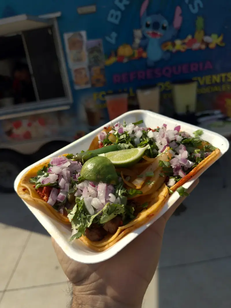Plate of tacos with onion, cilantro and lime at a Taqueria 4 Brothers taquiza