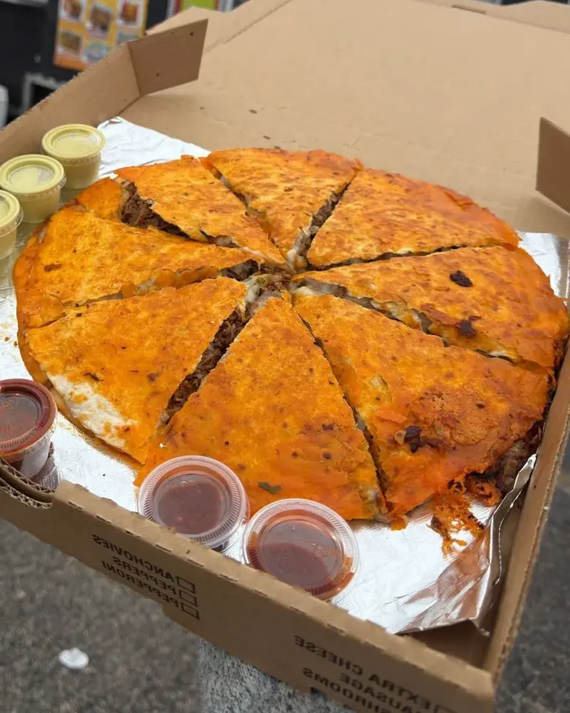 Close-up of sliced Pizza Birria in a takeout box